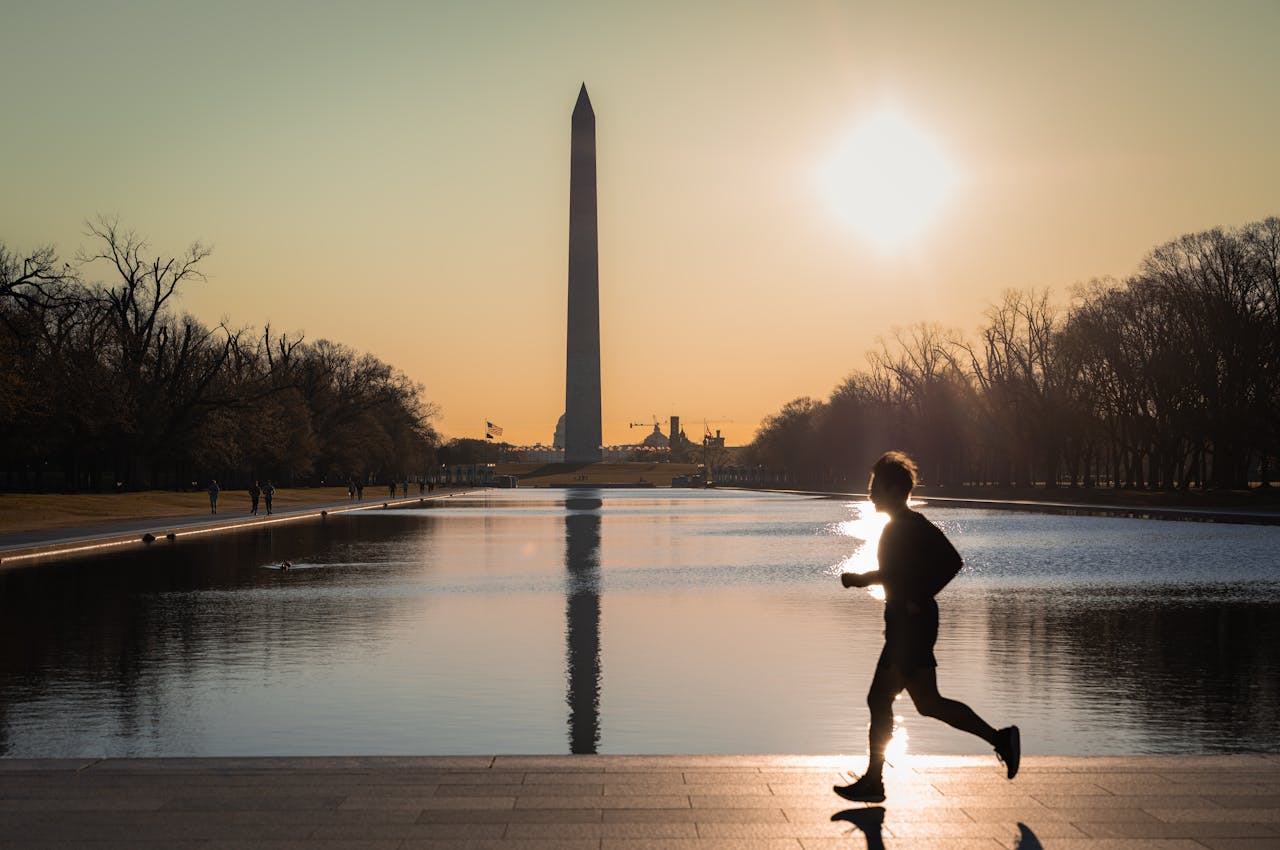 about-img A silhouette of a runner at sunset near the Washington Monument reflecting in the water.