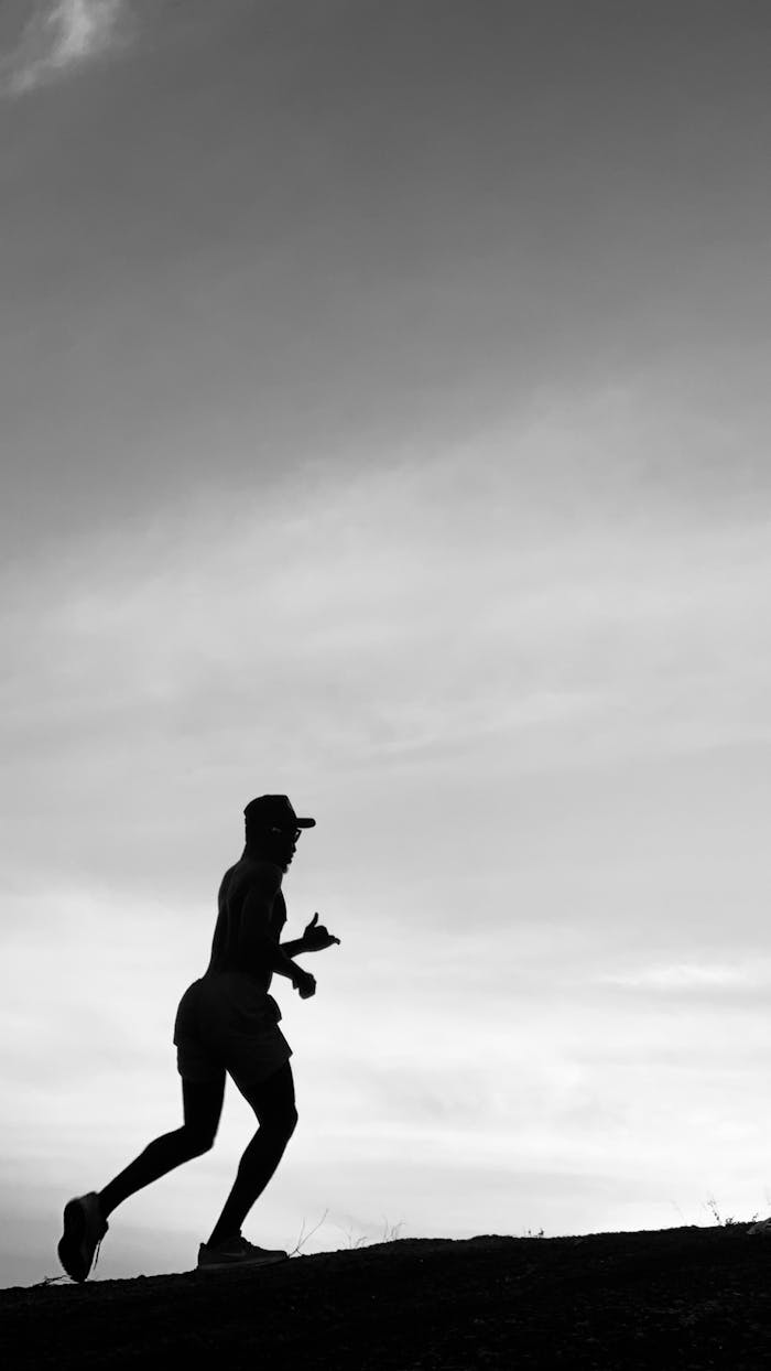 contact-img A silhouette of a man running uphill during twilight, emphasizing movement and fitness.