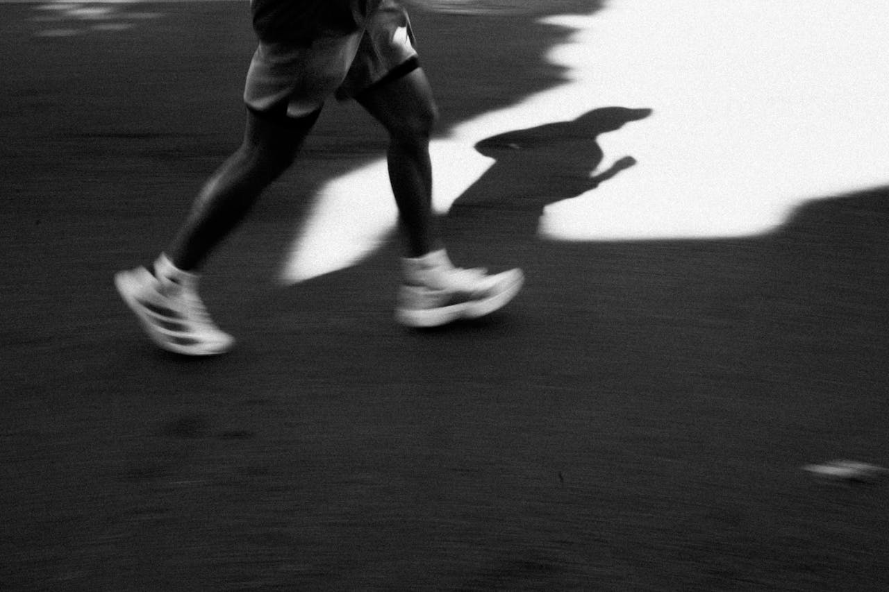 services-img Captivating black and white image of a runner's shadow casting on the pavement in motion.
