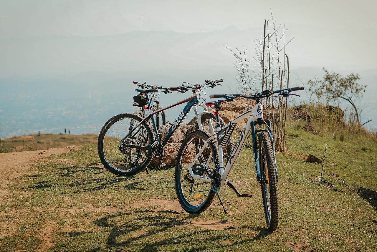 Two mountain bikes parked on a scenic hilltop path with a distant view of landscape.